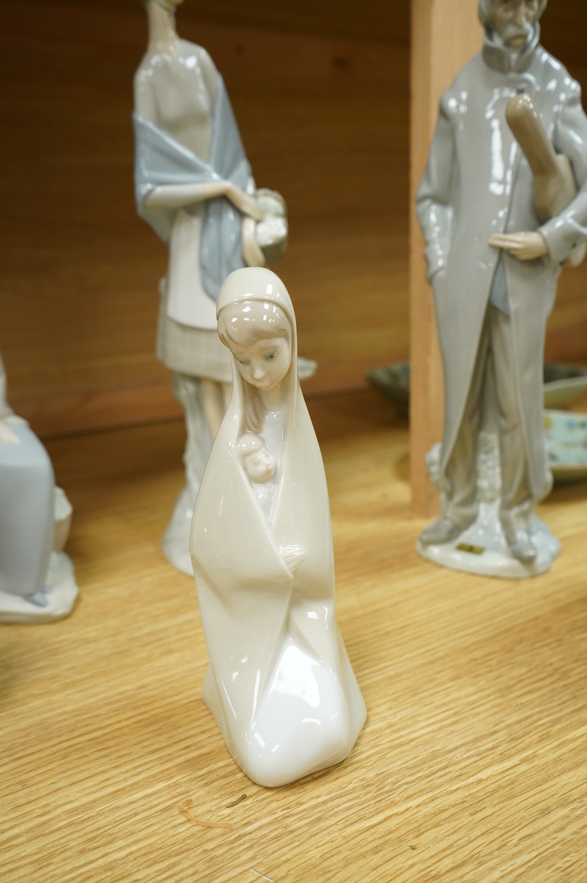 A group of Lladro figures: Tramp with violin, Bust of Mary Magdalene, Holy family, Girl with child, Young Shepherds, Girl with basket, girl with jug